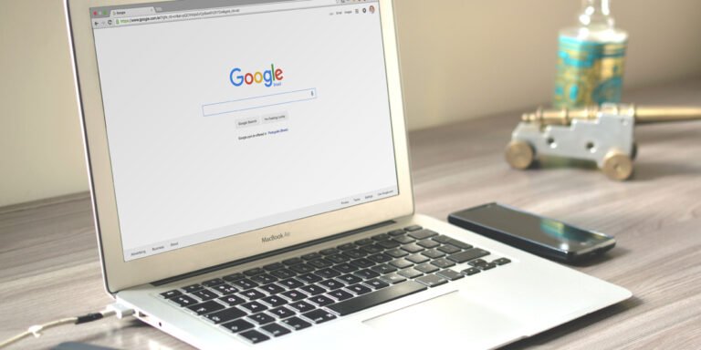 An open laptop sitting on a desk with the screen showing the Google Search engine.