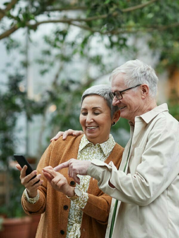 An older couple standing together looking a mobile device.