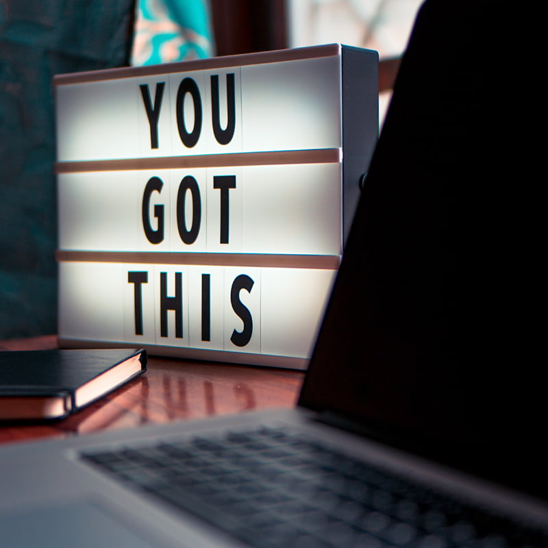 A sign sitting next to a computer with joined letters cards spelling out 'You Got This'.